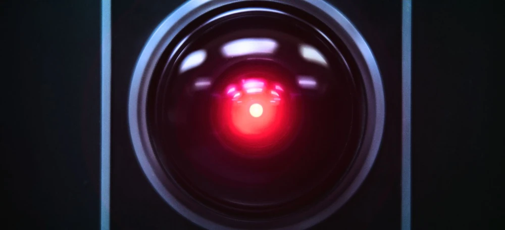 Photo of Hal 9000 from the movie 2001: A Space Odessey. Hal is a circle with a red dot in the middle representing this famous chatbot from the 80s.